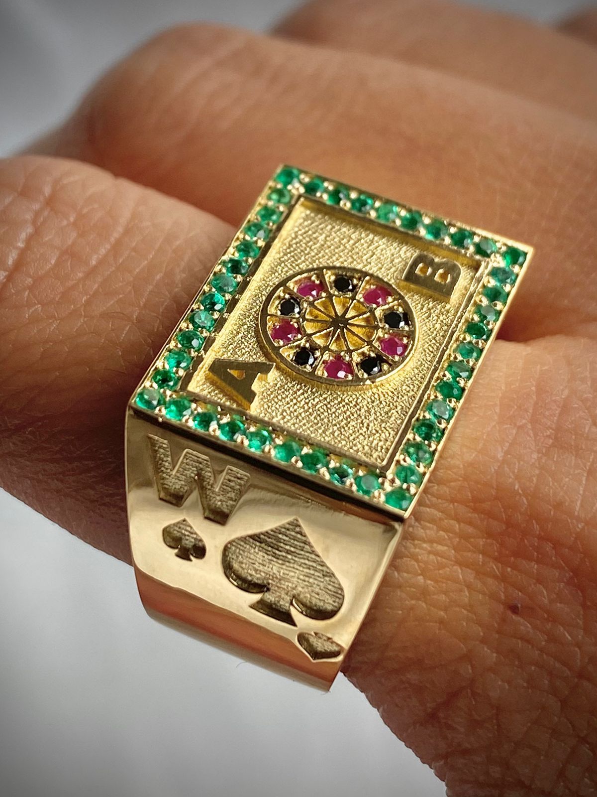 ANILLO RULETA INICIALES 0,40 CTS ESMERALDAS, 0,06 CTS DIAMANTES NEGROS, 0,06 RUBIES/ ORO AMARILLO 10,46GR